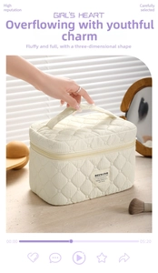 Detail of cream quilted makeup bag with soft texture, top handle, and brand label
