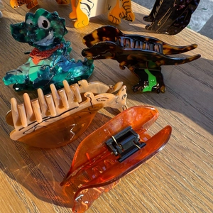 Detailed view of colorful acetate dinosaur hair claws in green and brown patterns