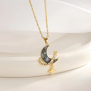 Detailed close-up of golden moon pendant with dark iridescent shell and star accents