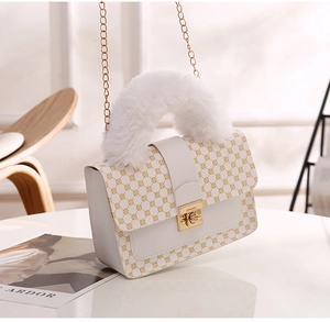 Detail of white printed handbag featuring plush fur handle and golden chain strap