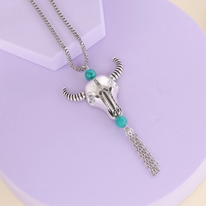 Vintage bull head necklace with turquoise beads and metallic tassels on a soft background