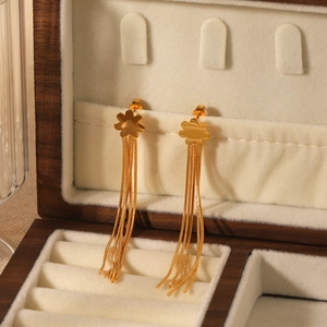 Detail of gold flower earrings with long metal tassels on a velvet jewelry box