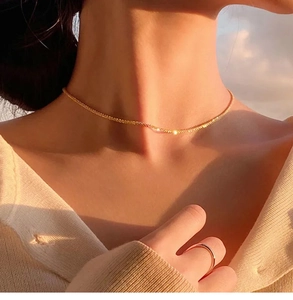 Detail of elegant gold twist chain necklace with shimmering metallic texture on model