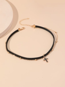 Dettaglio di un choker in velluto nero con catena a sfere dorate e ciondolo a croce