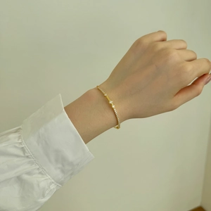 Elegant gold Mobius bracelet featuring sparkling zircon and opal stones on model's wrist