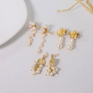 Baroque pearl earrings in gold fringe and bee designs on a clean white background