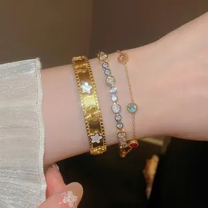 Gold-toned layered jewelry set with floral cuff, tennis chain, and gemstone bracelets
