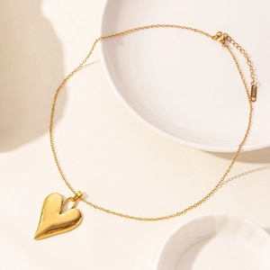 Close-up of gold heart pendant necklace with lobster clasp and S.steel engraved tag