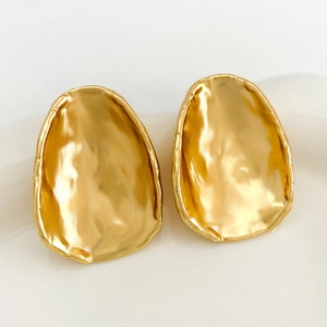 Macro shot of minimalist golden irregular geometric metal earrings with textured surface