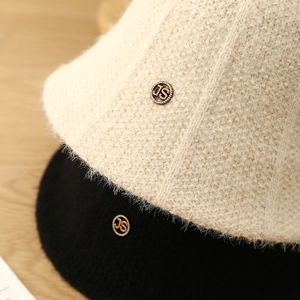 Close-up of plush knit bucket hats with rhinestone JS logo in cream and black colors