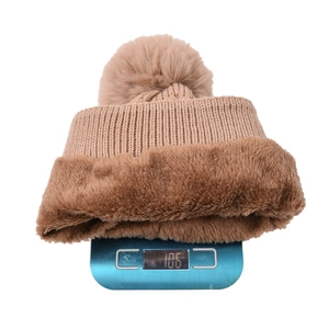 Detailed view of brown cable knit beanie with faux fur lining on a scale weighing 106g