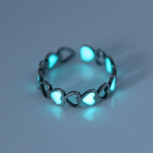 Macro shot of luminous heart-shaped ring glowing in the dark on stainless steel band