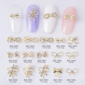 Various alloy 3D bow nail charms with pearls and rhinestones shown in 15 styles