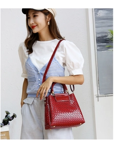 Detail of red embossed woven texture handbag with golden hardware and metal feet