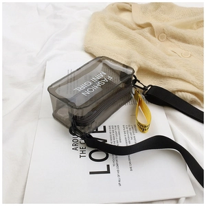 Macro detail of transparent grey PVC crossbody bag with fashion text and yellow strap