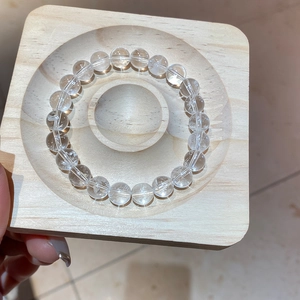 Macro shot of clear white crystal beaded bracelet on a square wooden display tray
