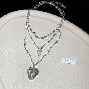 Three-layer silver heart pendant pearl necklace with embossed texture on ivory tray
