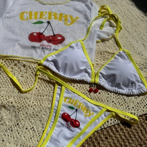 Detailed view of 3-piece cherry print bikini set with mesh cover-up and 3D cherry charm