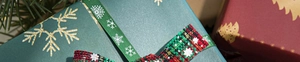 Close-up of red plaid bow on green snowflake gift box with festive pine needles