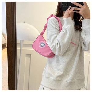 Pink fabric underarm bag with blue heart detail and ruffled strap shown in a mirror selfie