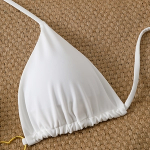 Detail of white triangle bikini top featuring a gold heart metal buckle and pleated hem