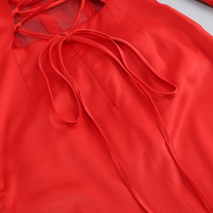 Detail of red satin dress featuring an elegant lace-up back design and silky texture