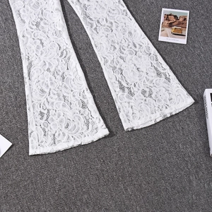 Detail of white lace flare pants showing intricate floral embroidery and sheer texture