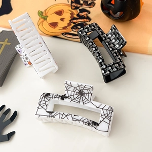 Detail of Halloween hair claws featuring spider web and pumpkin prints on orange background