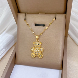 Detailed close-up of a luxury gold teddy bear pendant with sparkling crystals on a silk cloth