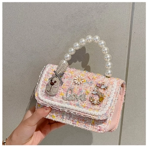 Close-up of pink tweed girls handbag with pearl handle and decorative charm details