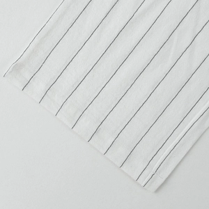 Dettaglio macro del tessuto in lino bianco traspirante con strisce nere e cuciture pregiate