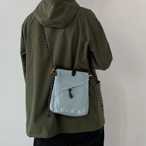 Detail view of light blue nylon crossbody bag with adjustable rope strap and zipper pocket
