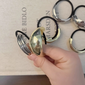 Minimalist metallic gold hair tie with sleek polished curved metal accent ring