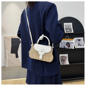 Detail of handwoven straw handbag with white leather patchwork and metallic buckle hardware