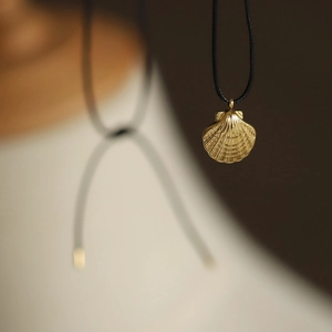 Close-up of golden shell pendant with black cord necklace for a beach vacation style