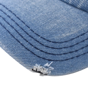 Close-up of distressed brim on washed blue denim baseball cap with reinforced stitching