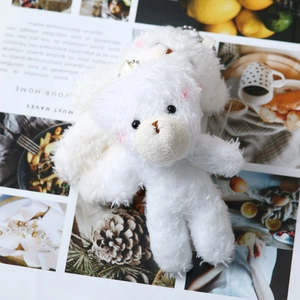 Close-up of white plush teddy bear charm with pink blush and soft fur texture
