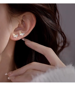 Close-up of S999 sterling silver butterfly stud earrings with colorful gemstones on a model