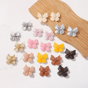 Mini faux leather butterfly hair clips in assorted metallic colors on wooden tray