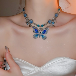 Détail du collier pendentif papillon en émail bleu avec perles sur un cou féminin