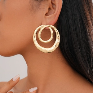 Detail of gold double-layered hammered round earrings worn showing size and texture