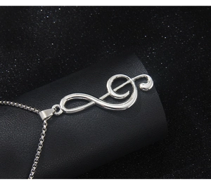 Macro shot of silver treble clef and infinity music pendant on black display