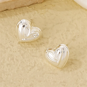 Macro view of silver heart earrings featuring a layered design and polished finish