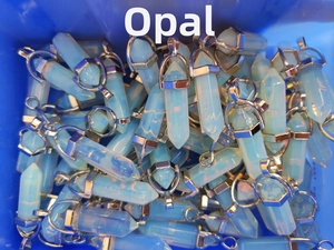 Detailed view of hexagonal opalite crystal pendants in bulk with silver metal caps
