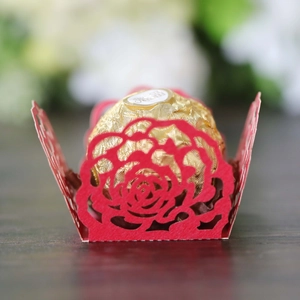 Close-up of laser-cut red rose paper candy wrapper for wedding party decoration