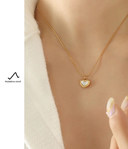 Macro view of heart-shaped stainless steel necklace with white shell inlay on gold chain
