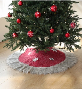 Macro shot of red Christmas tree skirt with white snowflake patterns and plush grey fur trim
