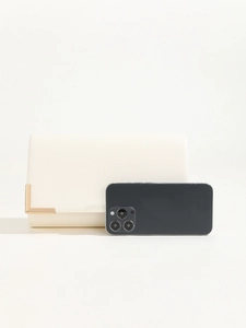 Detail view of a cream white PU leather clutch bag with gold trim and size reference