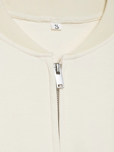 Détail du col d'un blouson bomber blanc crème avec zip métallique et étiquette de taille S