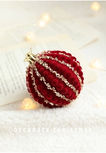 Detail of burgundy velvet Christmas ball with gold sequins and beads on white faux fur